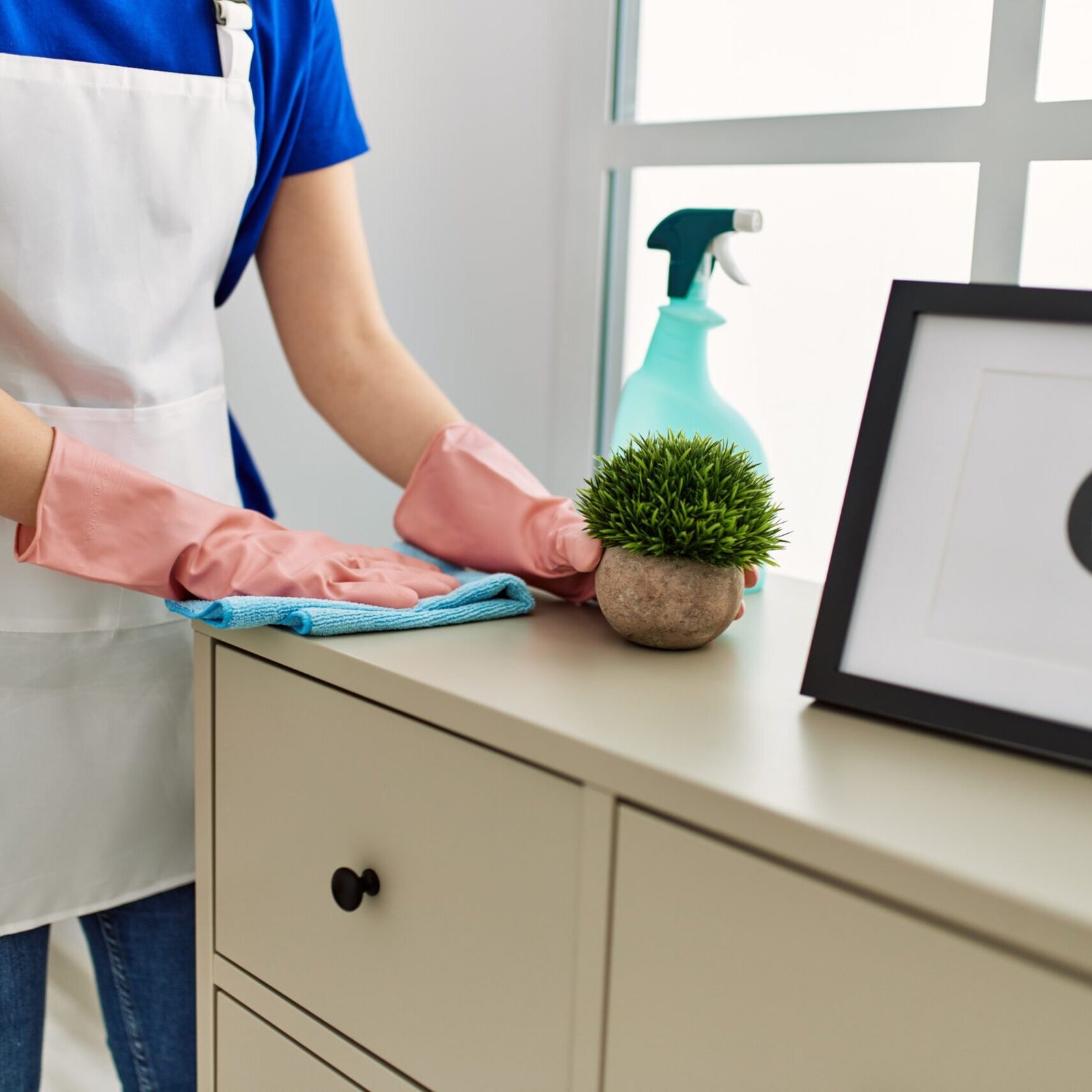 Woman cleaning table using rag and diffuser at home.