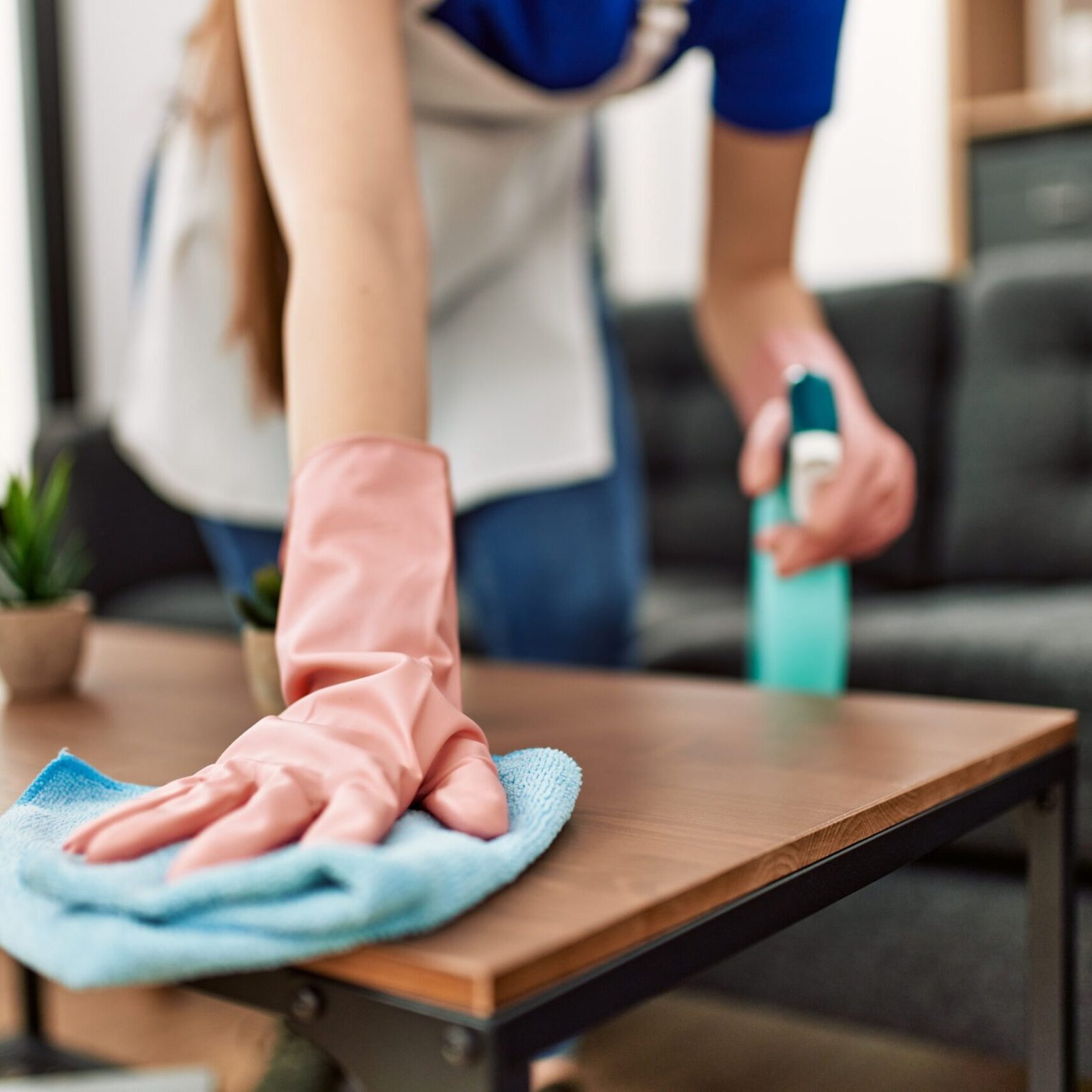 Woman cleaning table using rag and diffuser at home.